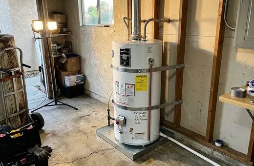 Gas tank water heater held by two seismic straps in the corner of a garage
